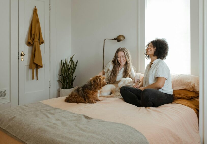 Foto bij Onderzoek lhbt - Een wereld van verschil met twee vrouwen en twee honden op bed