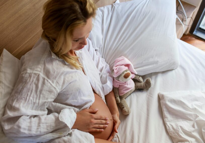 Foto van zwangere tiener in bed met knuffel, bij onderzoeksrapport Gewoon gezellig met zo'n buik