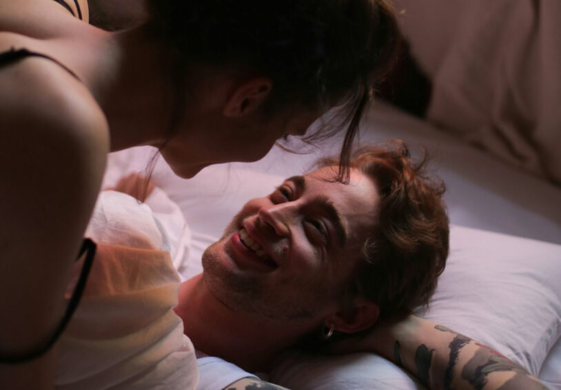 Foto van twee mensen die elkaar liefdevol aankijken in bed